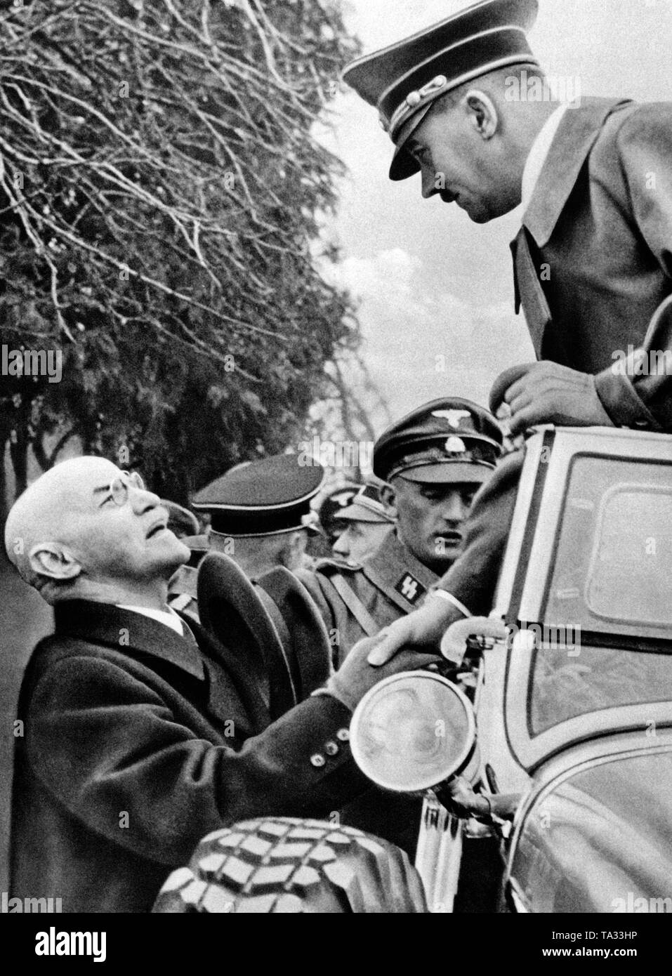 Adolf Hitler im Auto in der Nähe von Braunau am Inn, während durch Österreich fahren, das war von deutschen Truppen besetzt. Neben dem Auto seine ehemalige Grundschule Lehrer ihn Gruß ist. Stockfoto