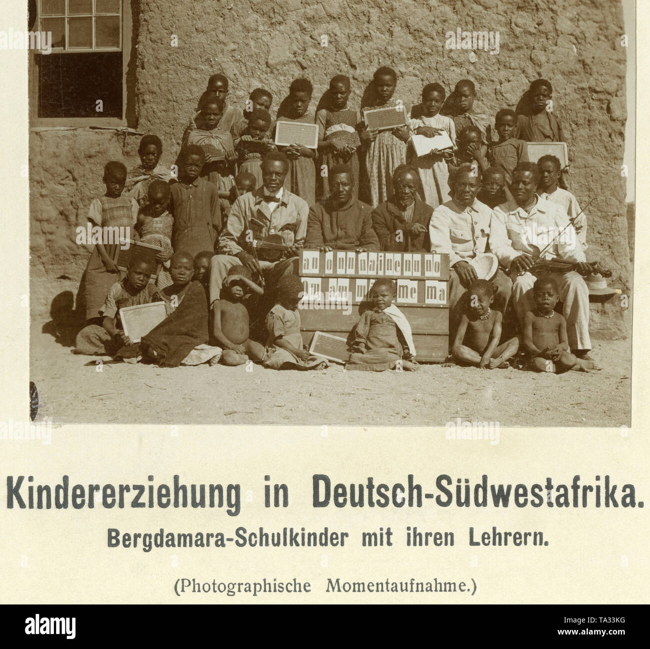 Eine Gruppe von Damara Schulkinder in Deutsch-Südwest-Afrika fotografiert mit fünf Lehrer vor einem Haus an der Wand. Stockfoto