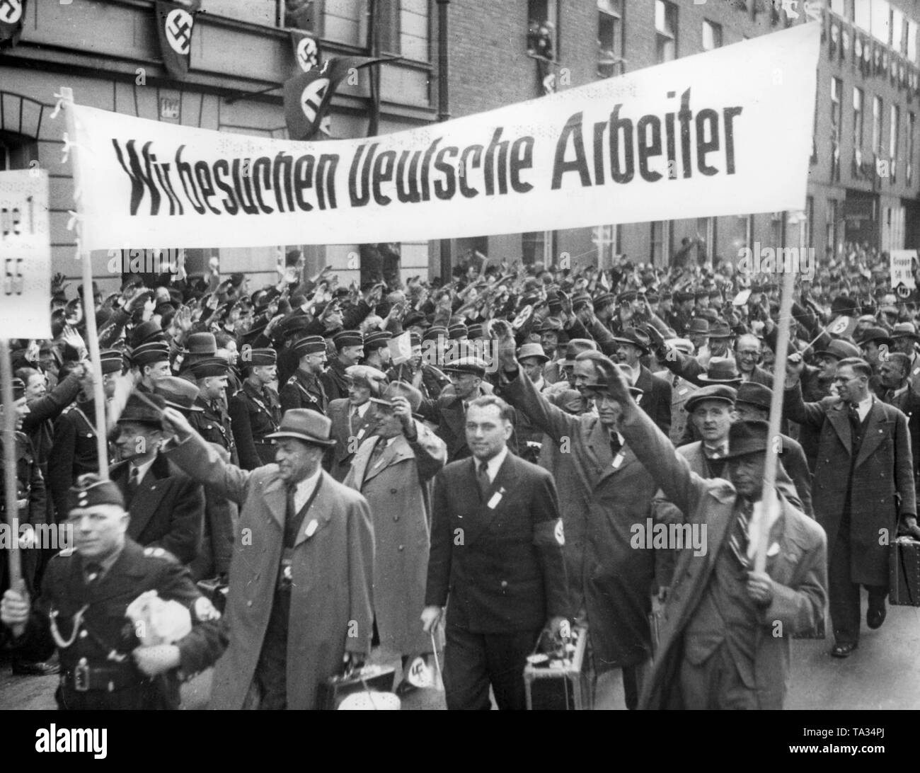 Nach dem Anschluss Österreichs, 2000 Wiener Arbeitnehmer mit besonderen Züge am Anhalter Bahnhof in Berlin kamen für eine Reise organisiert von der NS-Organisation "Kraft durch Freude" ('Stärke durch Freude"). Hier sind Sie marschieren zu ihren Quartieren. In der Front, ein Banner mit der Aufschrift "Wir besuchen die deutschen Arbeiter". Stockfoto