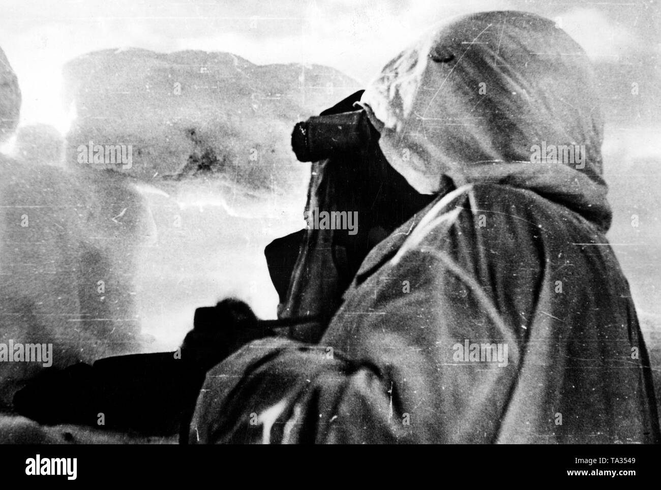 Ein deutscher Soldat, mit einem Schnee Mantel getarnt, schaut hinter eine Mahnwache der sowjetischen Position gebaut von eisblöcke. (PK-Foto) Stockfoto
