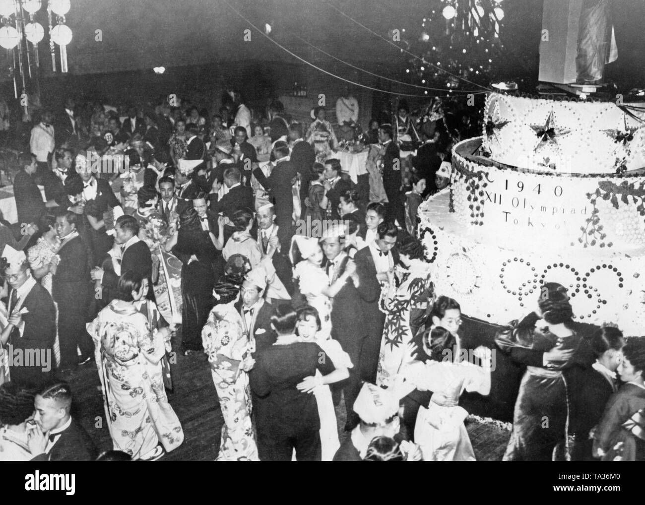 Blick über die tanzende Gäste von einer Weihnachtsfeier in Tokio. Auf der rechten Seite ist eine große Torte mit der Aufschrift "1940 XII Olympiade Tokio", die bevorstehenden Olympischen Spiele in Japan zu feiern. Stockfoto