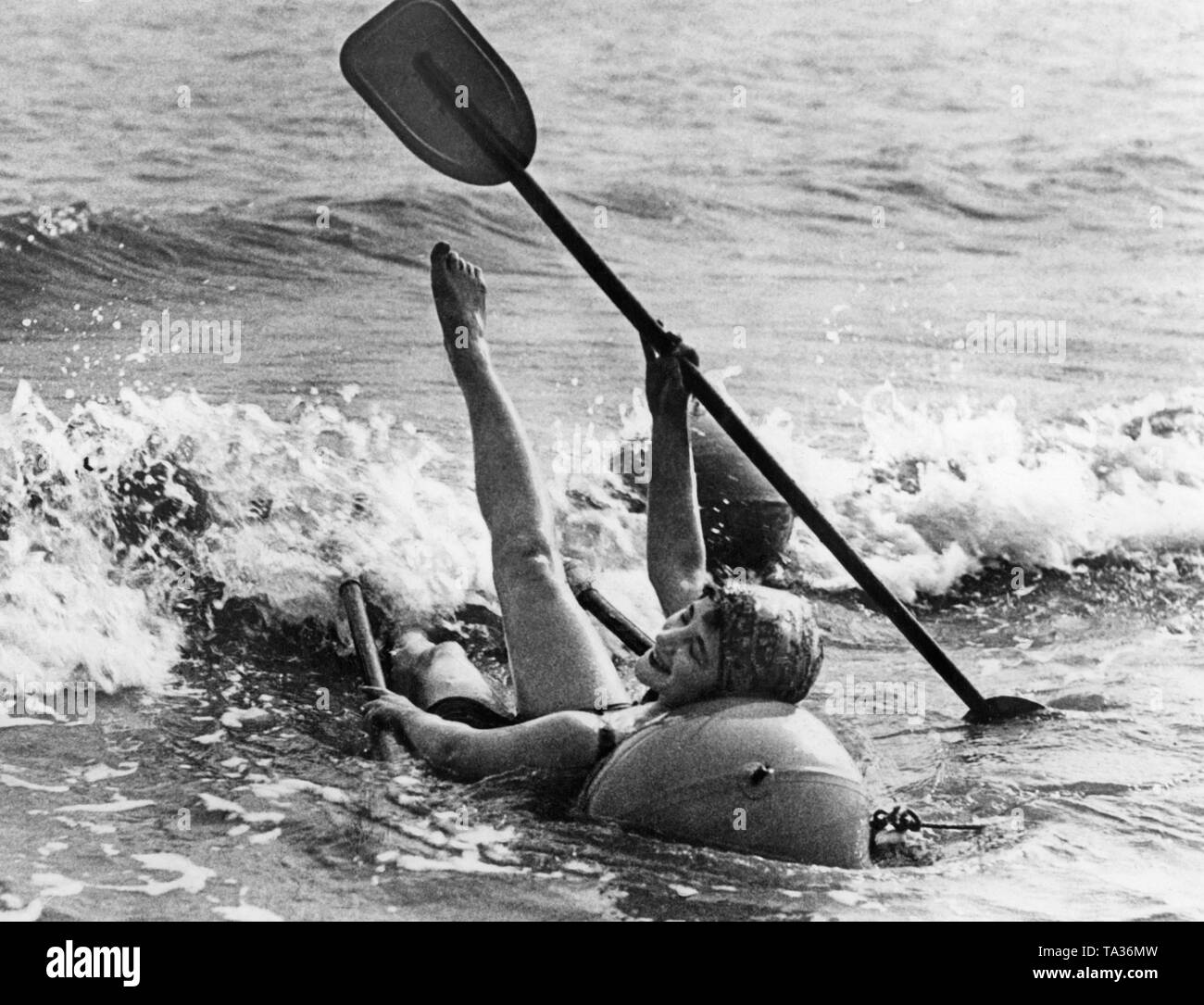 Eine Frau am Strand Urlaub Paddles glücklich in einem Meer Stuhl (Undatiertes Foto). Stockfoto