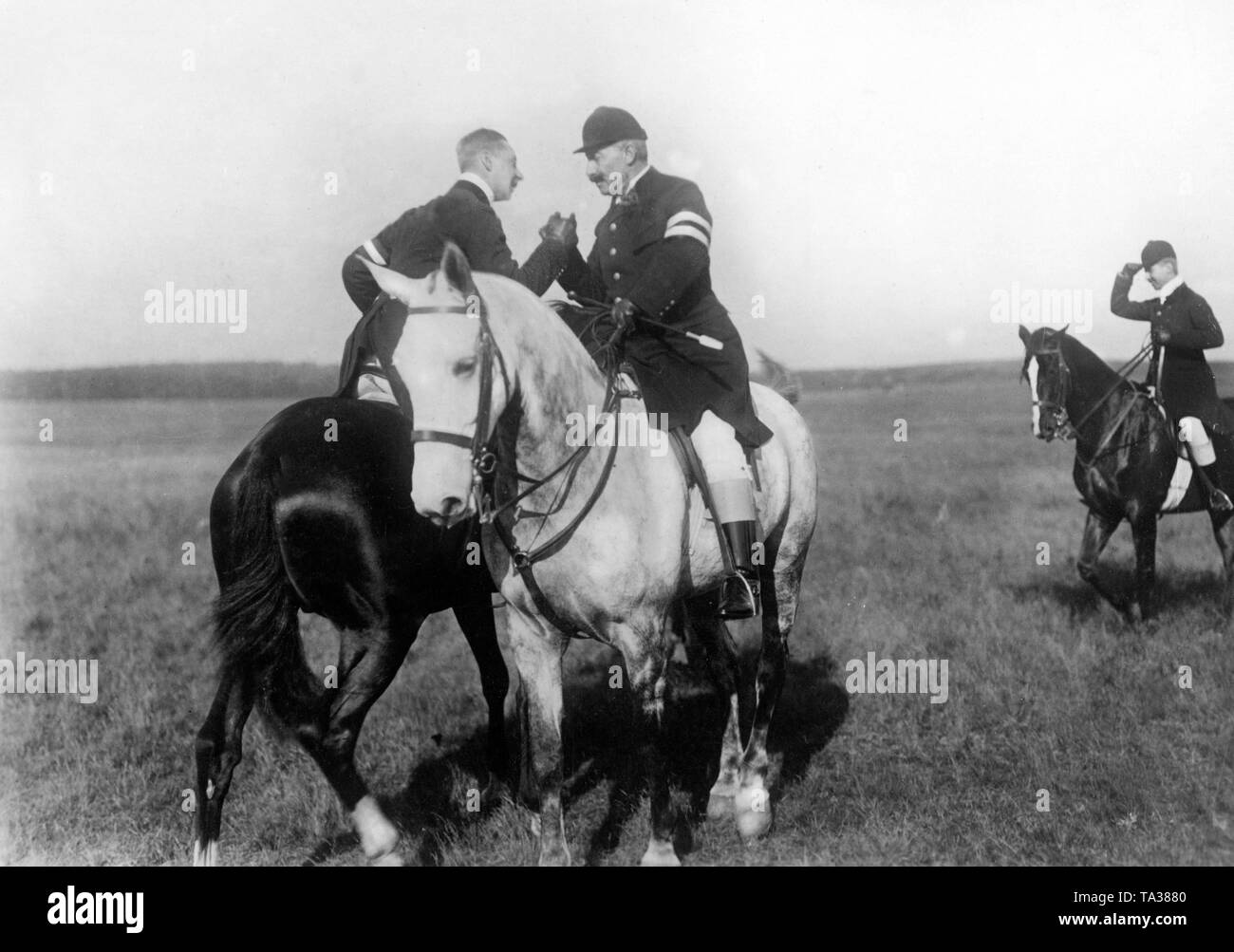 Kronprinz Wilhelm (links) und sein Vater Kaiser Wilhelm II (rechts) sind die Hände schütteln beim Sitzen auf ihren Pferden. Stockfoto