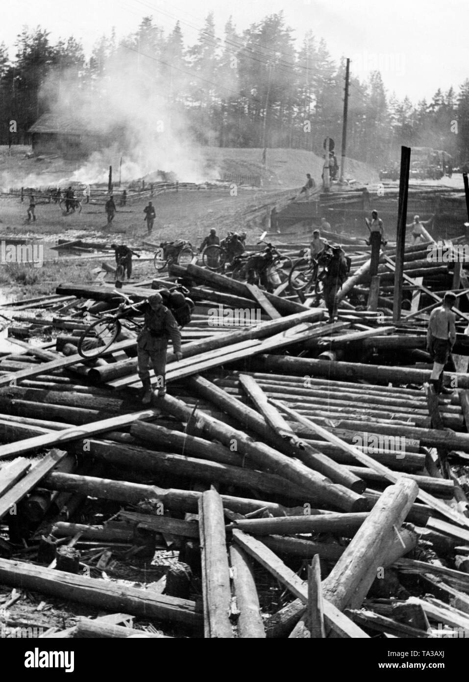 Ein Deutscher Fahrrad Bataillon wird durch eine zerstörte Holzbrücke. Stockfoto