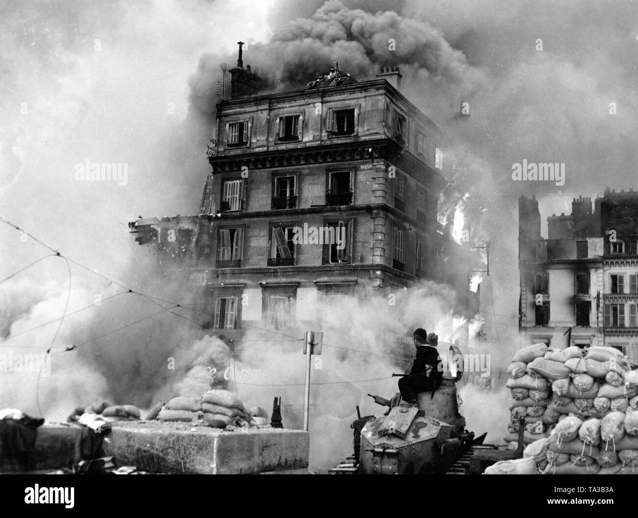 Zwei deutsche Soldaten sitzen auf einem zerstörten französische Renault FT Tanks und die Feuer um sie herum tobt. Stockfoto