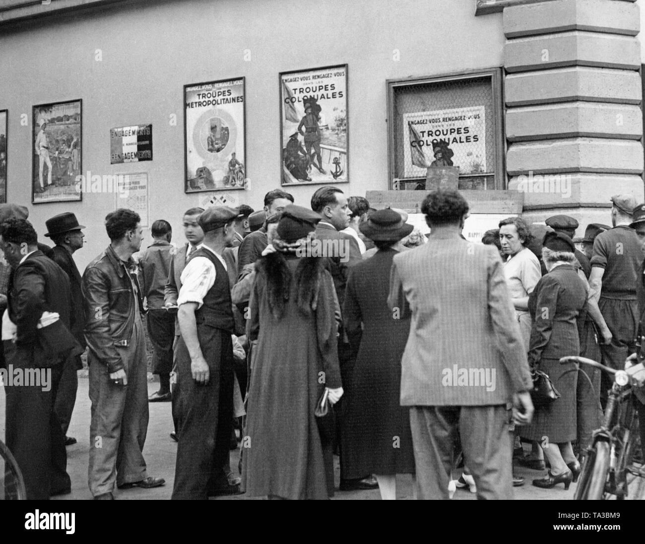 Männer und Frauen stehen vor Plakaten ruft zur Mobilisierung in Paris. Im Laufe des Sudetenlandes Krise, die teilweise Mobilisierung der französischen Streitkräfte auftritt. Adolf Hitler provoziert einen internationalen Konflikt mit Sudetenland Krise, um das Sudetenland an das Deutsche Reich zu Anhang. Stockfoto