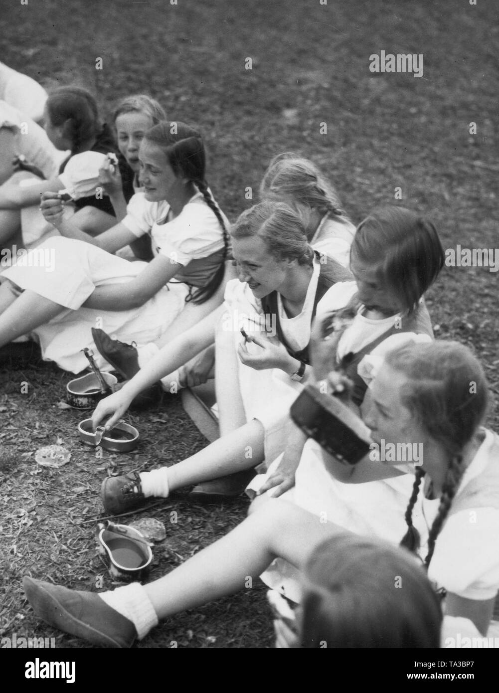 Mädchen des Jungmaedel Untergau 198 am Darm Alt-Glienicke essen von den Abdeckungen der Kochgeschirr. Stockfoto