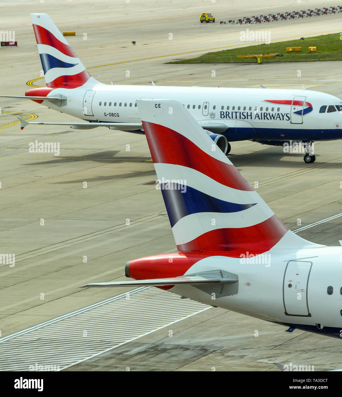 Der Flughafen London Gatwick, ENGLAND - April 2019: Schwanzflosse eines British Airways Jet am Flughafen Gatwick mit einem anderen Flugzeug der Fluggesellschaft in der backgro Stockfoto