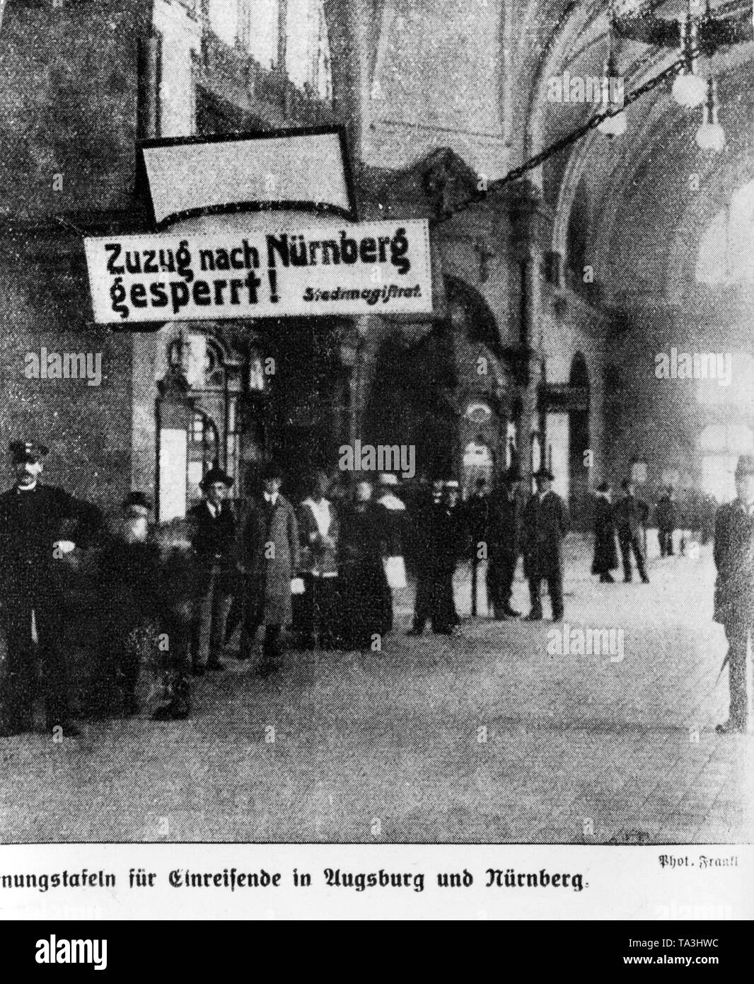 Passanten in der Aula der Nürnberger Hauptbahnhof. Über ihnen hängt ein Schild mit der Aufschrift: "Zustrom nach Nürnberg blockiert ist, Stadt Magistrat." Stockfoto