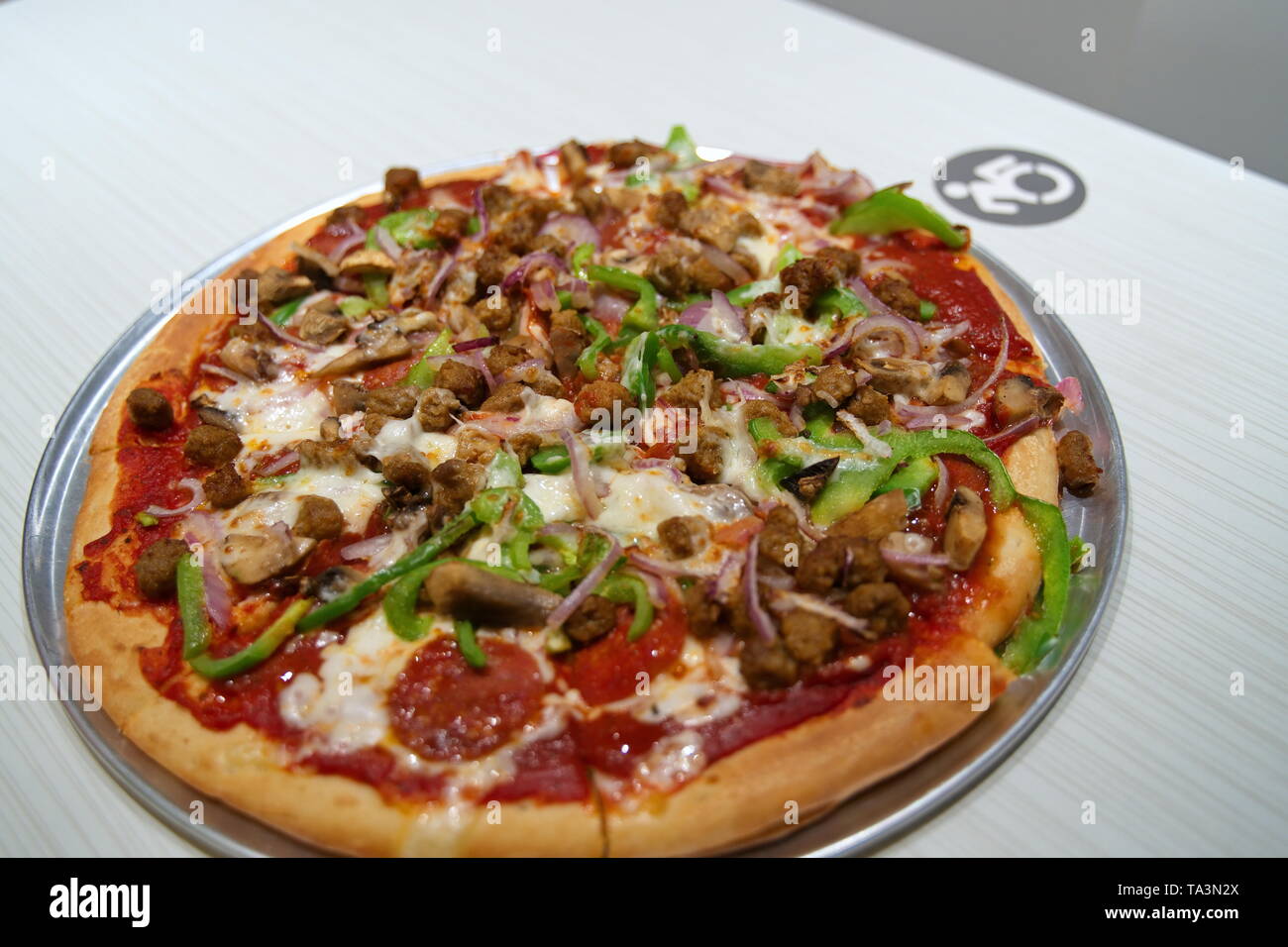Eine heiße Pizza, sitzend auf einem Handicap markierten Tabelle für körperlich behinderte Personen vorbehalten. Stockfoto