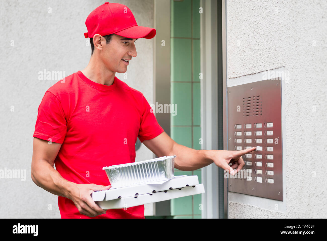 Pizza Delivery Man Kisten über die Gegensprechanlage Stockfoto