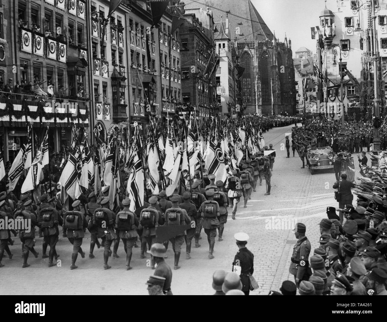 Parade der flagbearers des Stahlhelm Vergangenheit Adolf Hitler (stehend in einem Automobil auf den so genannten "Adolf-Hitler-Platz, heute der wichtigste Markt) auf der Nürnberger Rallye der NSDAP. Im Hintergrund die St. Sebaldus Kirche, auf der rechten Seite, die Schoener Brunnen. Stockfoto