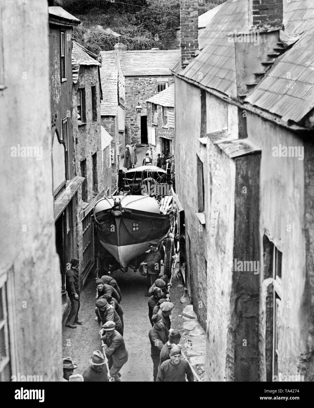 Die Bewohner des Dorfes Tintagel in Cornwall ein rettungsboot durch die engen Gassen des Dorfes für eine Übung ziehen. Stockfoto