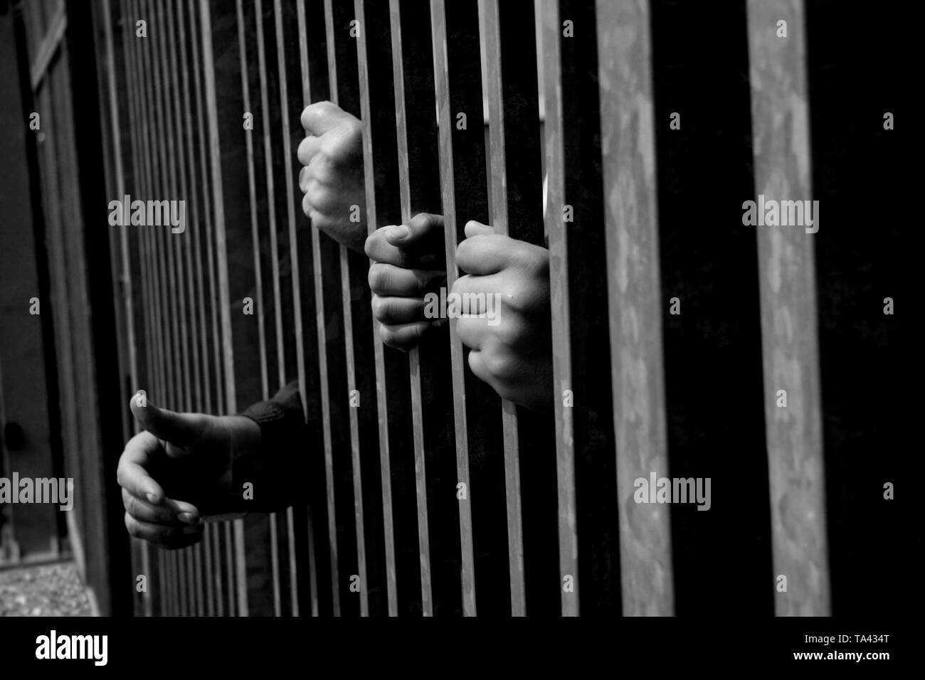 Hände halten und dem Erreichen von starken Eisenstangen. Gefängnis oder Eingewanderte und Flüchtlingskrise. Dramatische Grenzzaun oder Konzept. Schwarz-weiß Foto. Stockfoto