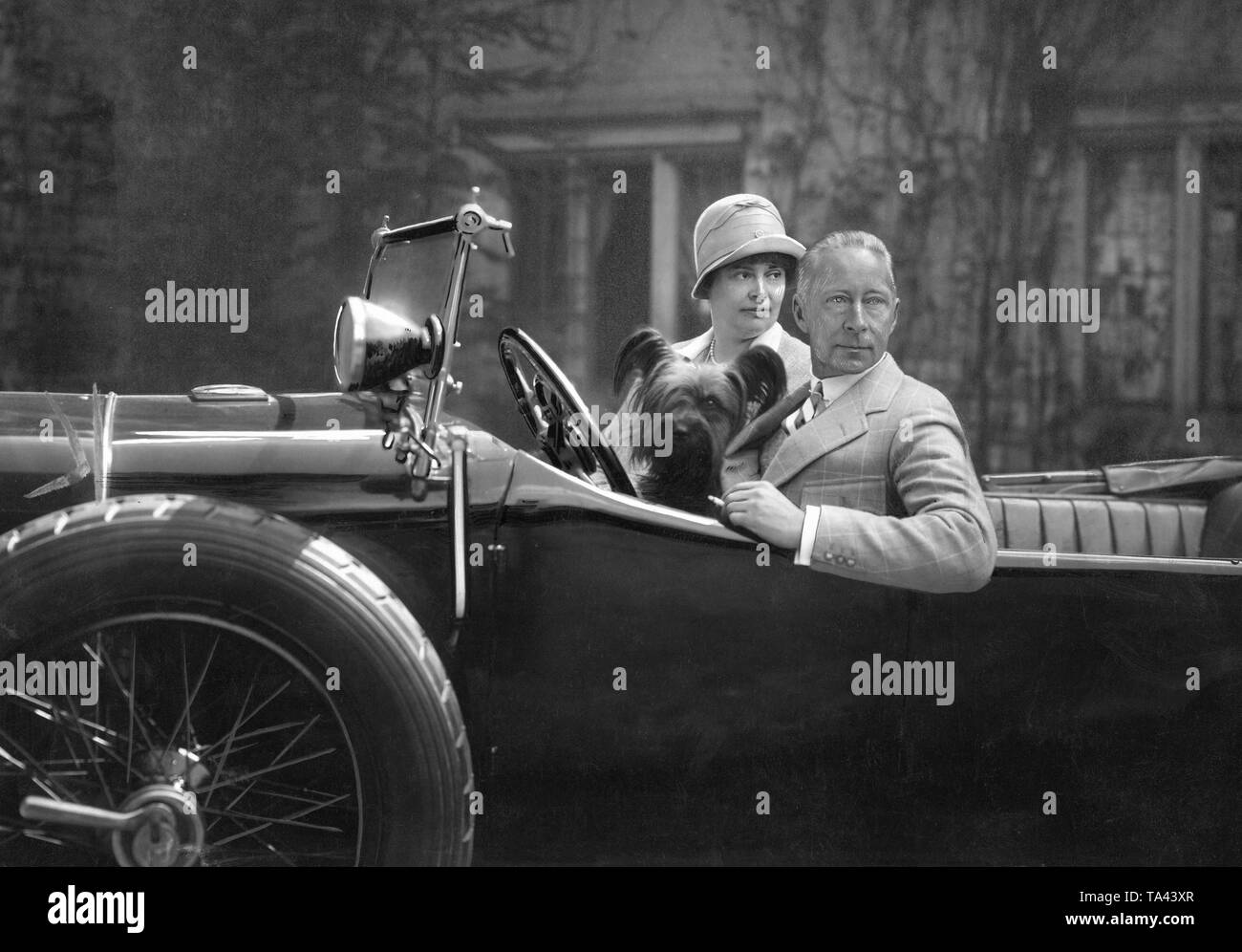Kronprinzessin Cecilie und Kronprinz Wilhelm von Preußen sitzen in einem Auto mit einem ihrer Hunde - anscheinend bereit für die Abreise. Stockfoto
