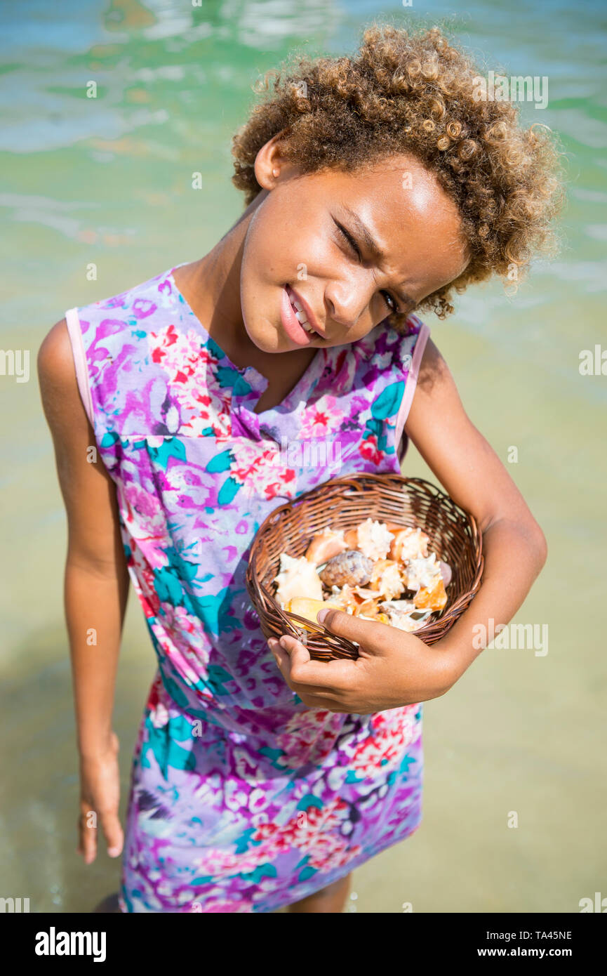 CAIRU, Brasilien - Februar 2018: Eine junge Brasilianerin verkauft souvenir Muscheln aus einem kleinen geflochtenen Korb für Besucher Anreise auf Bootstouren. Stockfoto