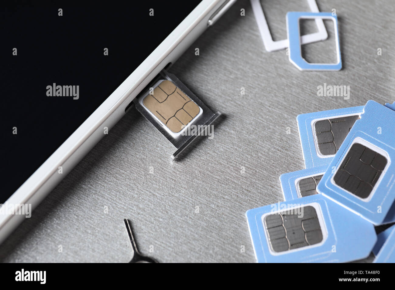 Mobiltelefon mit SIM-Karten auf grauem Hintergrund, Nahaufnahme Stockfoto