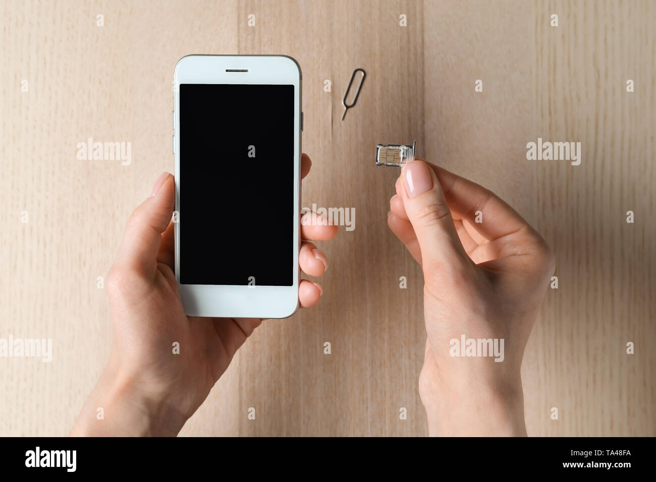 Frau Einlegen der SIM-Karte in das Mobiltelefon, Ansicht von oben Stockfoto