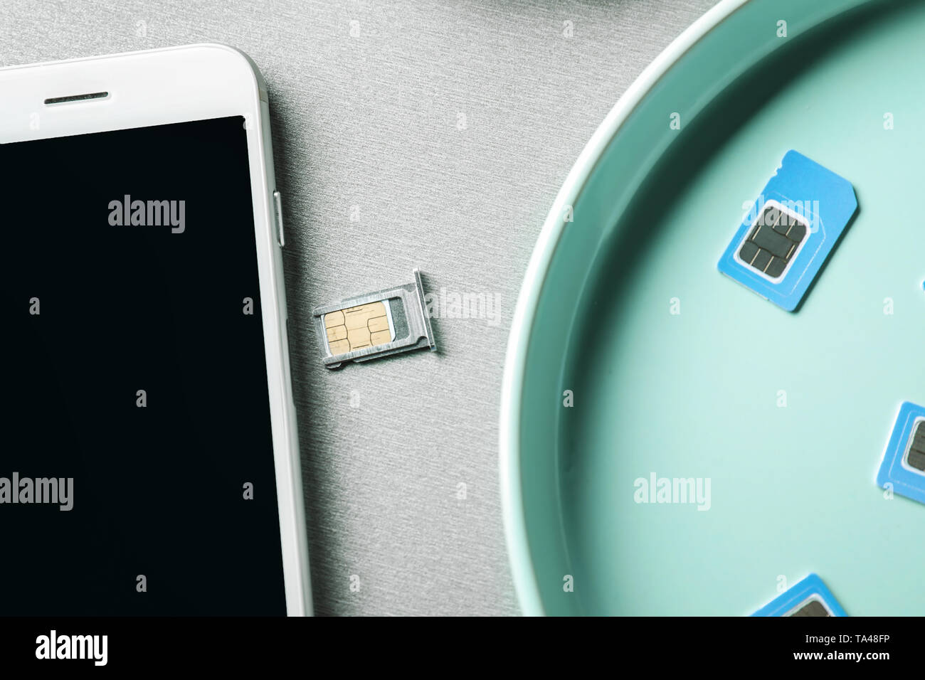 Mit SIM-Karten und Handy auf grauem Hintergrund Platte Stockfoto