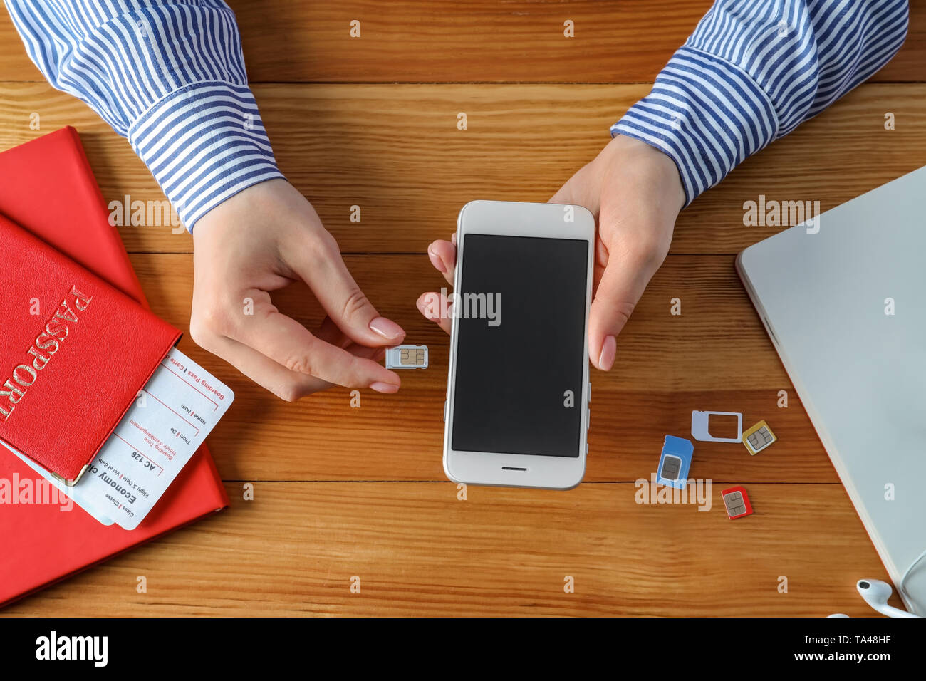 Frau Einlegen der SIM-Karte in das Mobiltelefon auf hölzernen Tisch Stockfoto