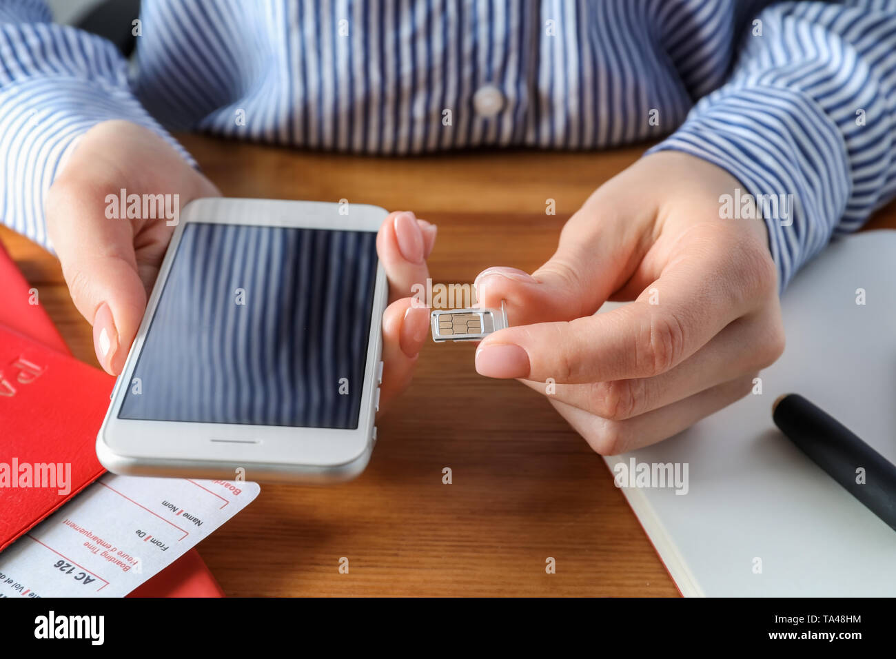 Frau Einlegen der SIM-Karte in das Handy an den hölzernen Tisch, Nahaufnahme Stockfoto