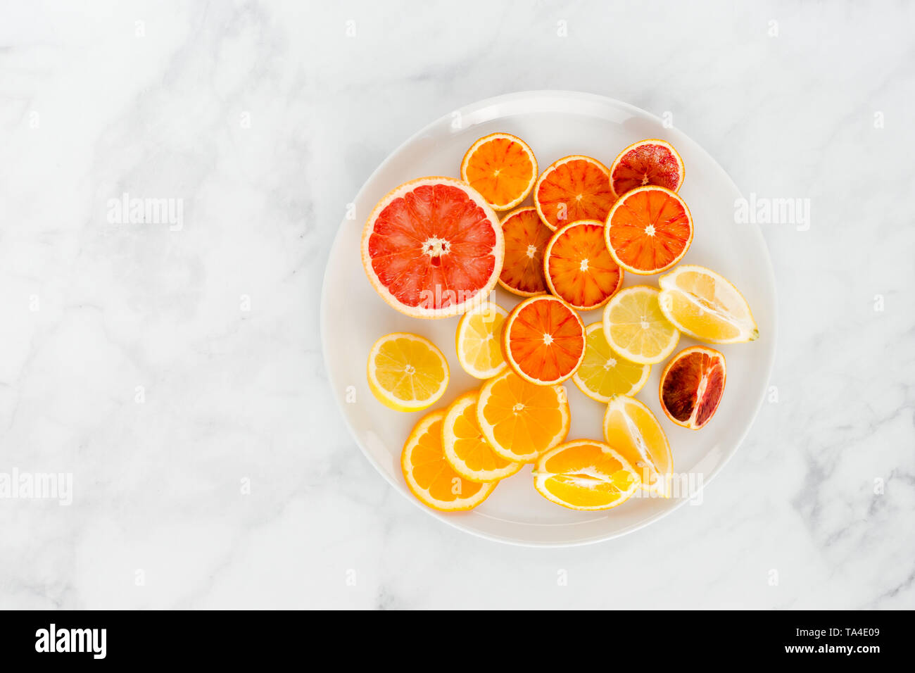 Schneiden sie Orangen, Orangen, Zitronen und Grapefruit auf eine große weiße Platte und weißem Marmor Hintergrund mit viel Platz kopieren. Ansicht von oben. Stockfoto