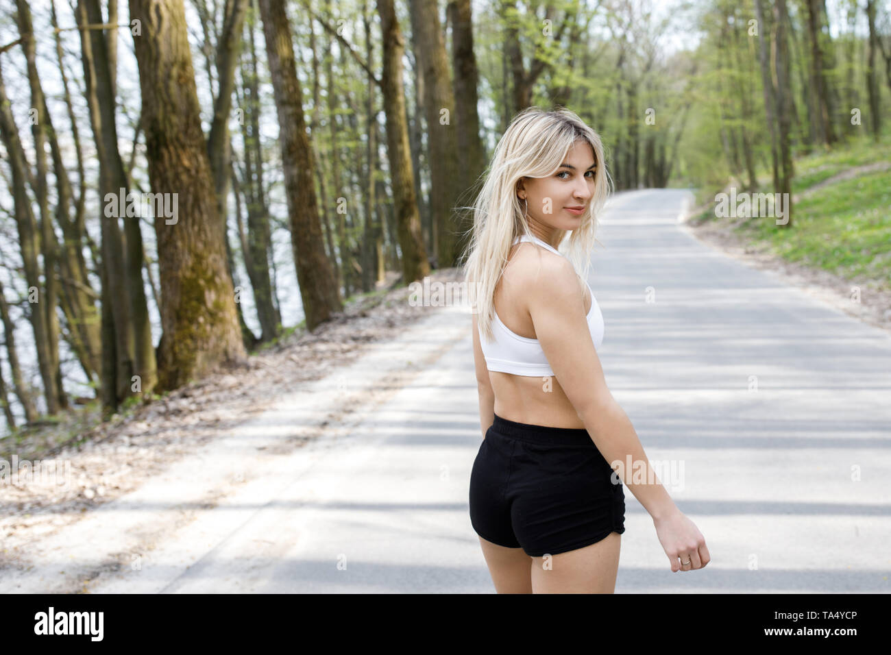 Eine junge, hübsche Mädchen blond läuft draußen in den Wäldern in der Nähe der See und die schöne Landschaft. Sportliche Aktivität. Übung im Freien. Stockfoto