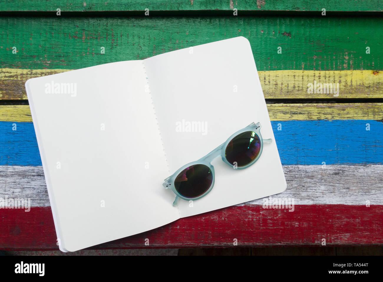 Öffnen Sie leere weiße Seite Buch auf bunten Holz- Hintergrund, Dekoration mit Sonnenbrillen Mode Stockfoto