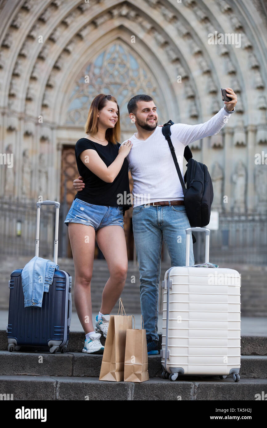 Lächelnd weibliche und männliche stehend mit Gepäck auf der Straße und Unter selfie Stockfoto