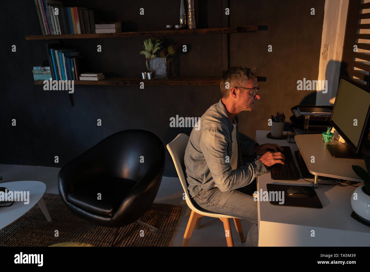 Reifer Mann mit Computer im Wohnzimmer Stockfoto