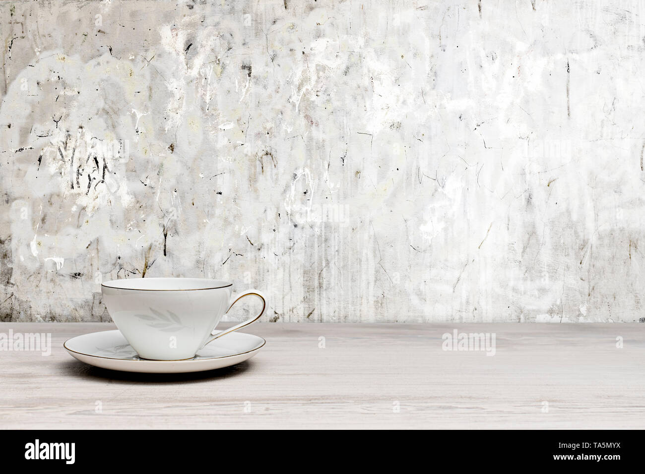 Vintage Teetasse auf einem weißen Holztisch, texturierte Wand Stockfoto
