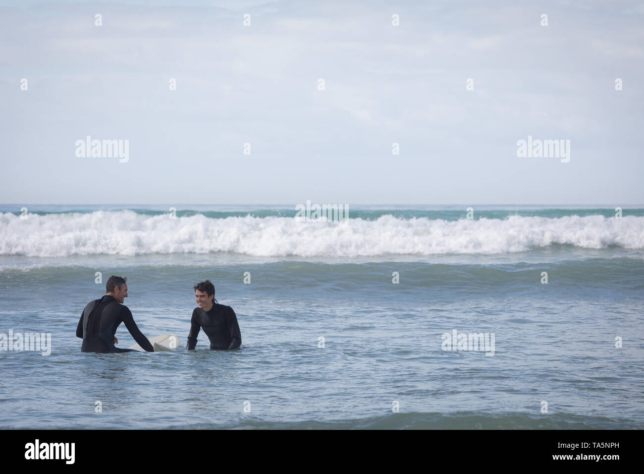 Vater und Sohn surfen mit Surfbrett im Meer Stockfoto
