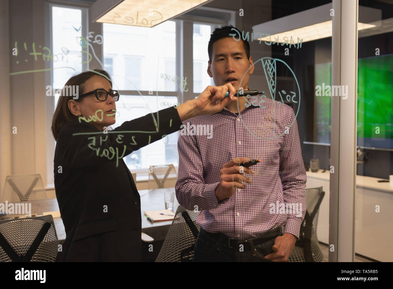 Geschäftsfrau zeigen Wachstum Chart zu Ihrem Kollegen auf Glas Wand Stockfoto