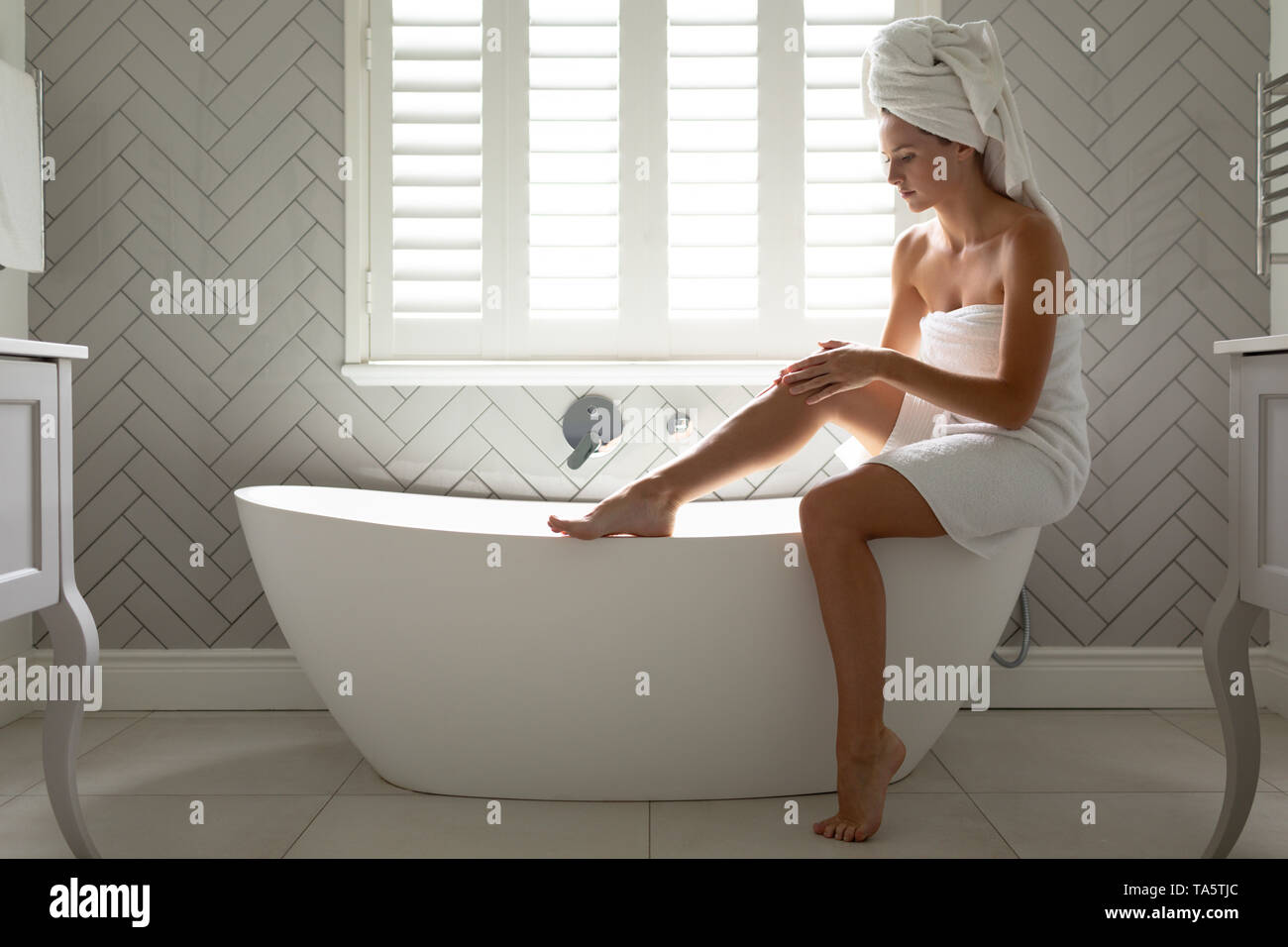 Schöne Frau ihre Beine massieren auf der Badewanne im Bad Stockfoto