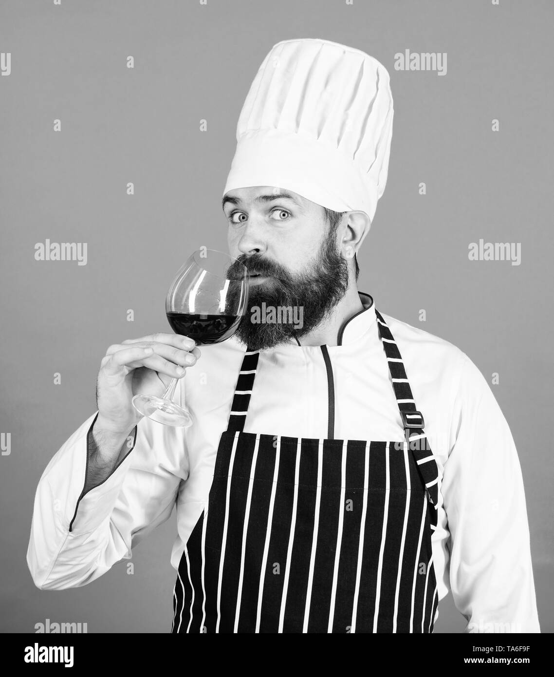 Das ist perfekter Wein. Happy bärtiger Mann. Dieser Wein ist einfach perfekt. Zuversichtlich männlichen sommelier Prüfung Glas mit Wein. Professioneller Koch Kochen in Uniform. Alkoholisches Getränk. Rotwein in Glas. Stockfoto