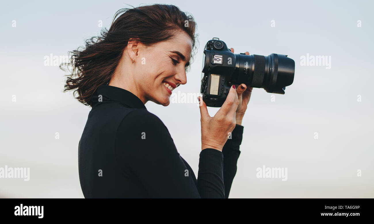 Professionelle Fotografin mit DSLR-Kamera fotografieren. Junge Frau mit Kamera Aufnahmen im Freien. Stockfoto
