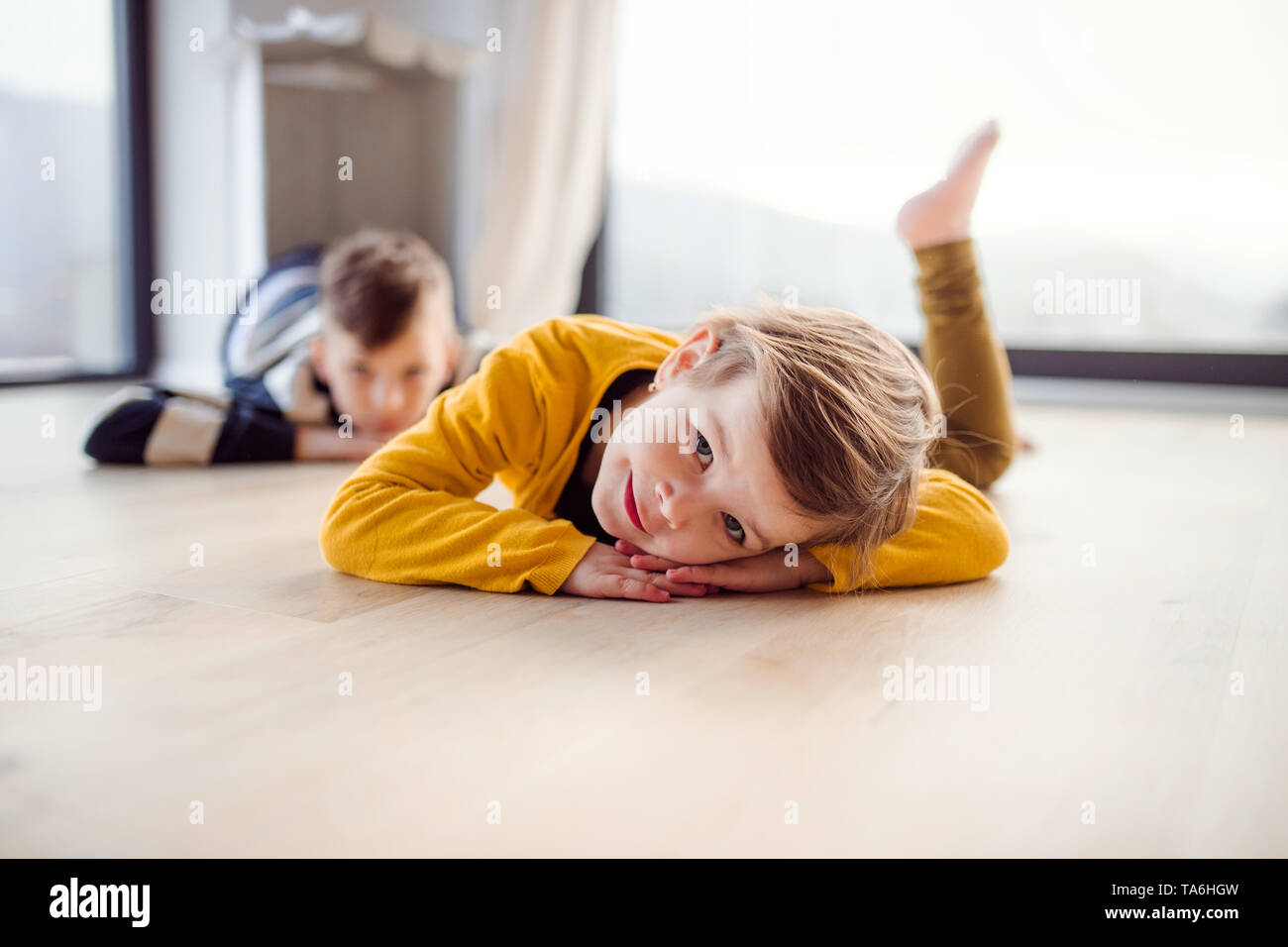 Zwei glückliche Kinder liegen auf dem Boden zuhause zu Hause. Stockfoto