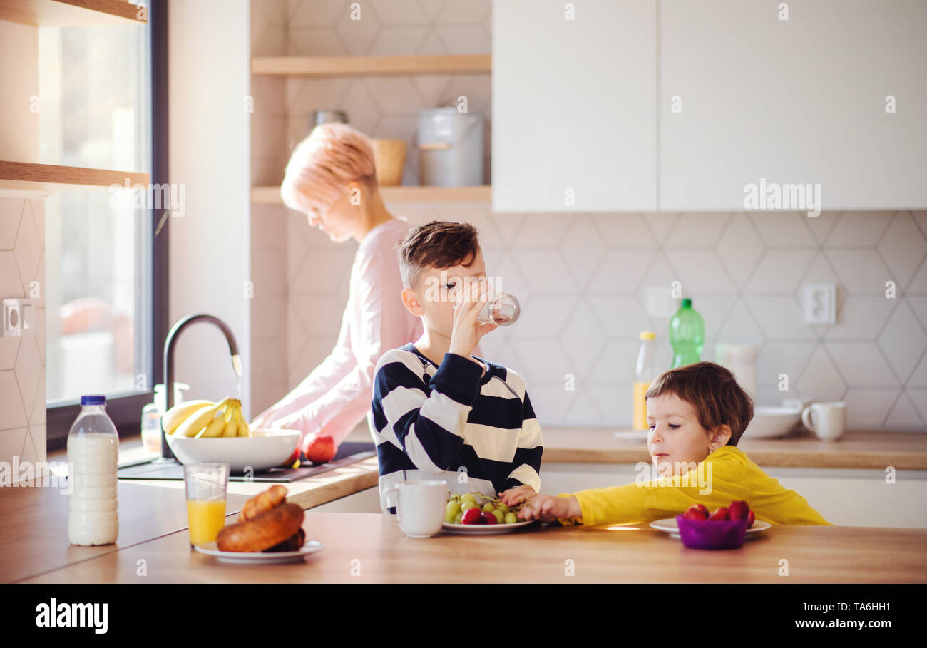 Eine junge Frau mit zwei Kindern das Essen der Frucht in einer Küche. Stockfoto
