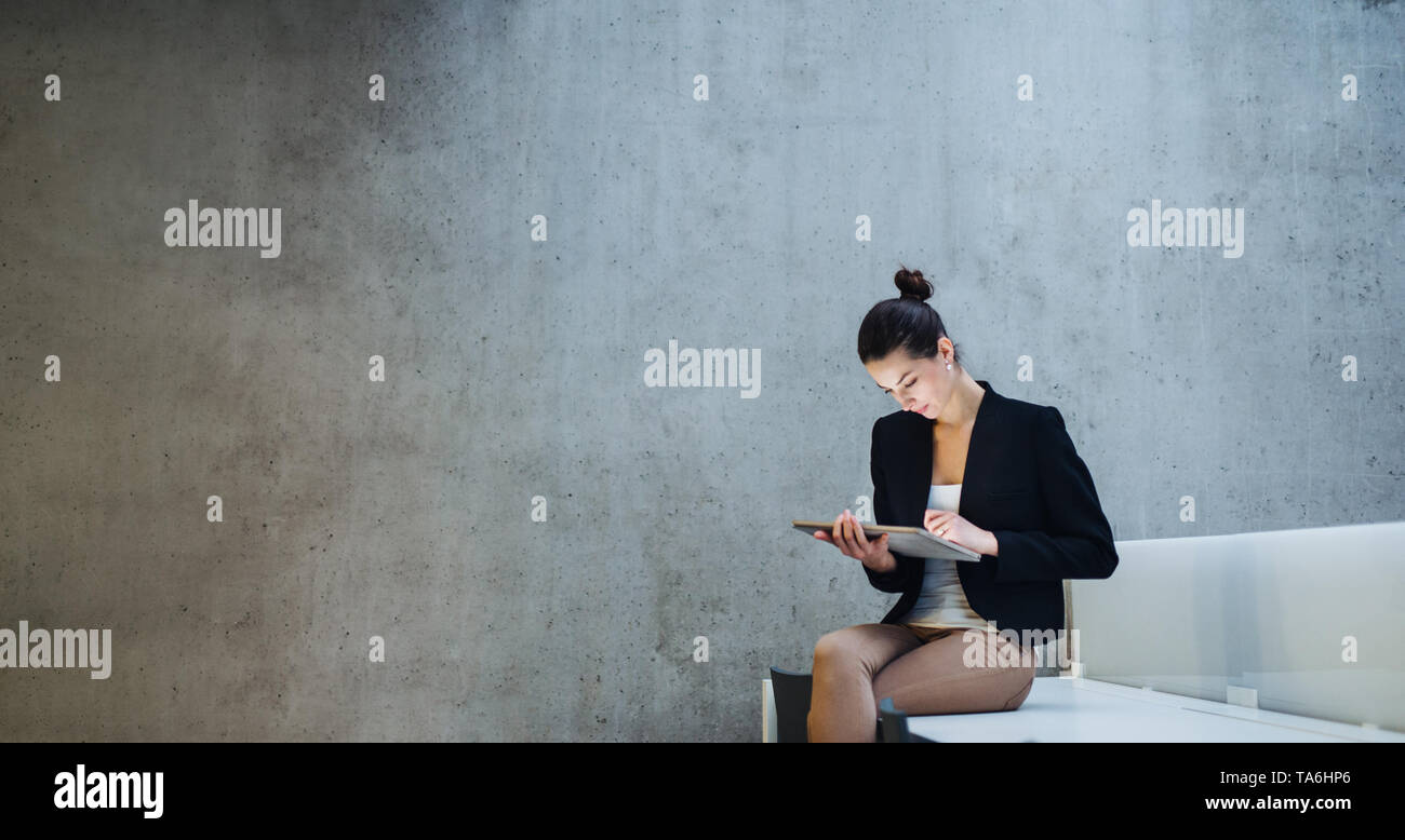 Junge student oder Geschäftsfrau, sitzen am Schreibtisch im Zimmer in einer Bibliothek oder einem Büro, mit Tablette. Stockfoto