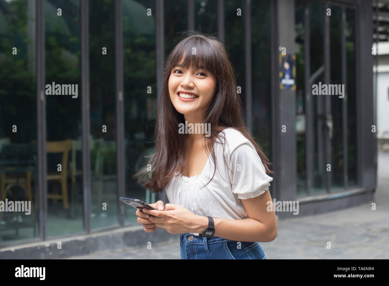 Gerne asiatische Frau mit smart phone Vor dem Restaurant Stockfoto