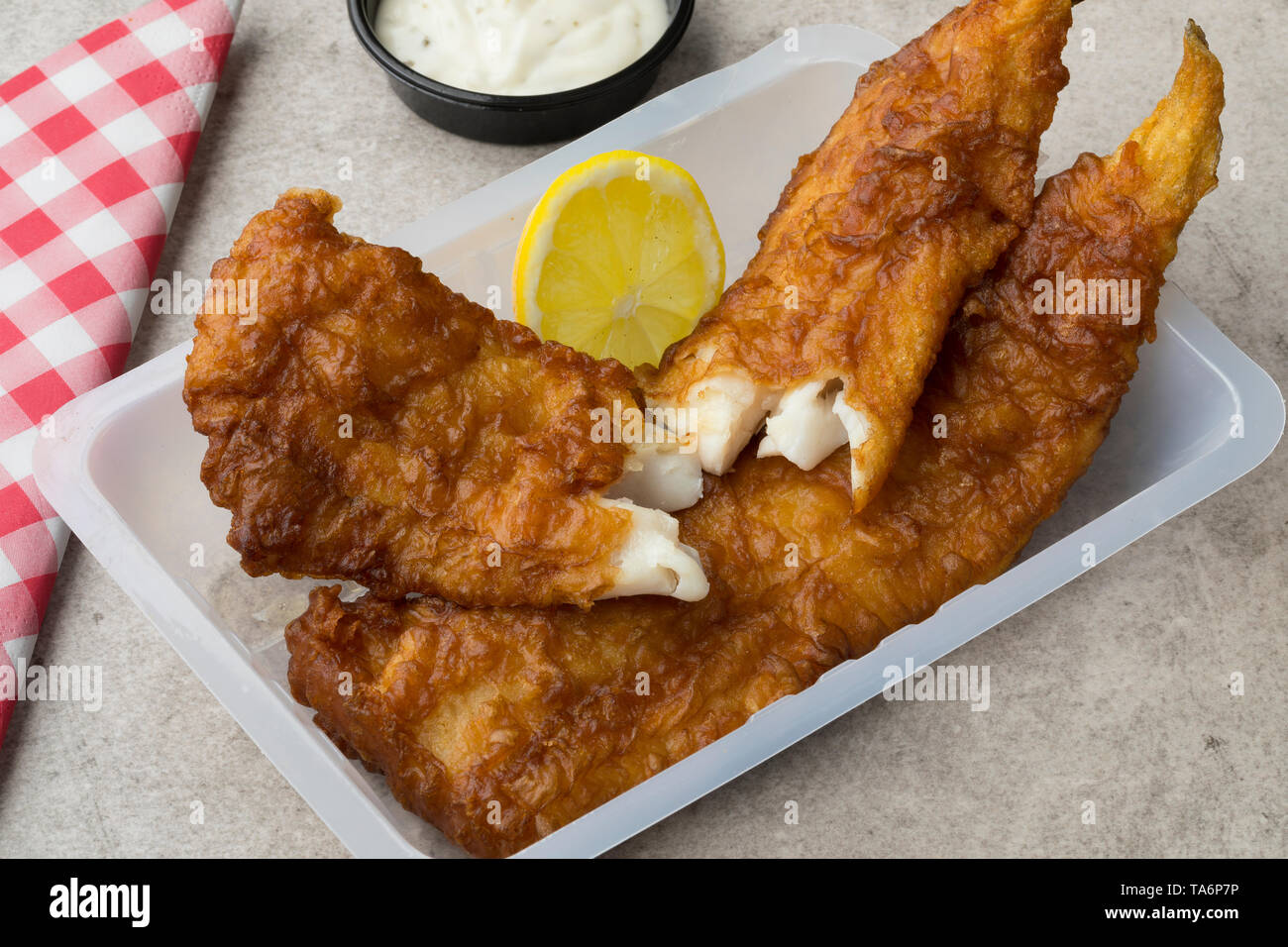 Frittierter Fisch Filet, genannt lekcurbek in Niederländisch, serviert in einer Plastikschale mit Sauce und Zitrone Nahaufnahme Stockfoto