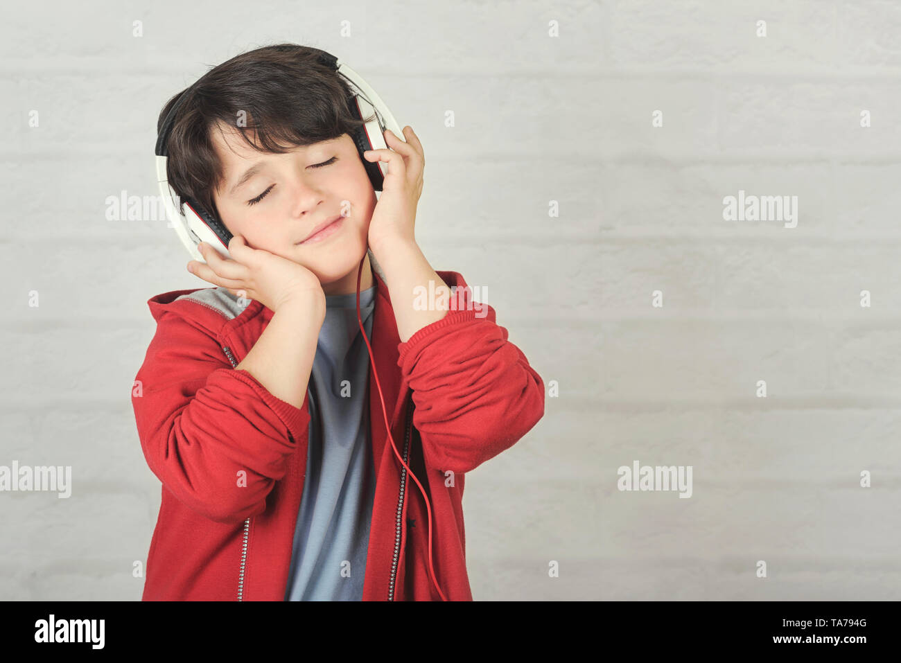 Glückliches Kind in Kopfhörer gegen Ziegel Hintergrund Stockfoto