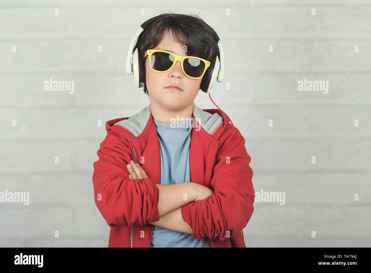 Schwere Kind mit Sonnenbrille und Kopfhörer gegen Ziegel Hintergrund Stockfoto
