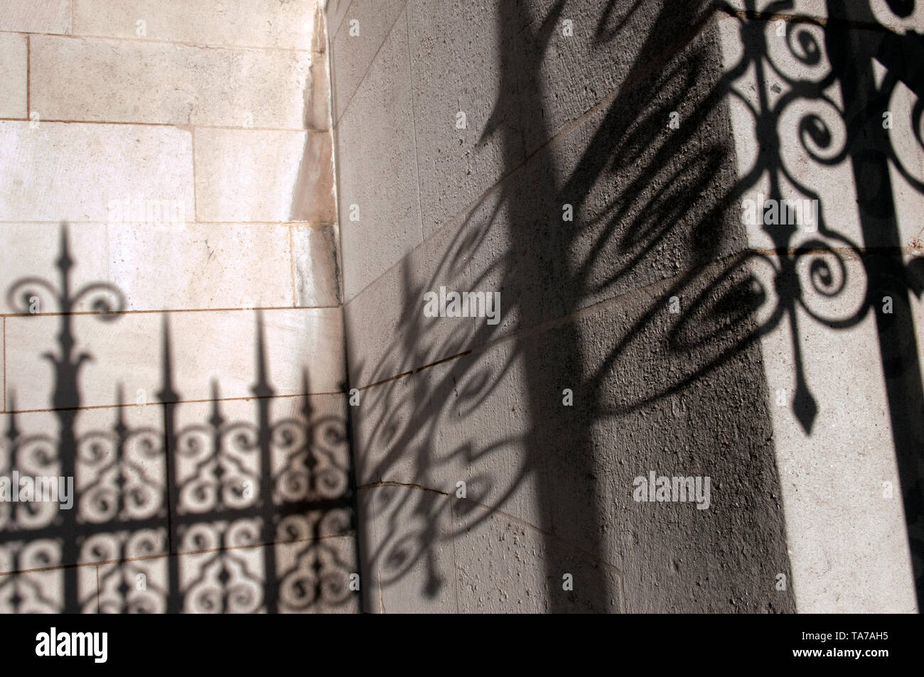 Der Schatten der Schmiedeeiserne Geländer gegen eine Mauer aus Stein Stockfoto