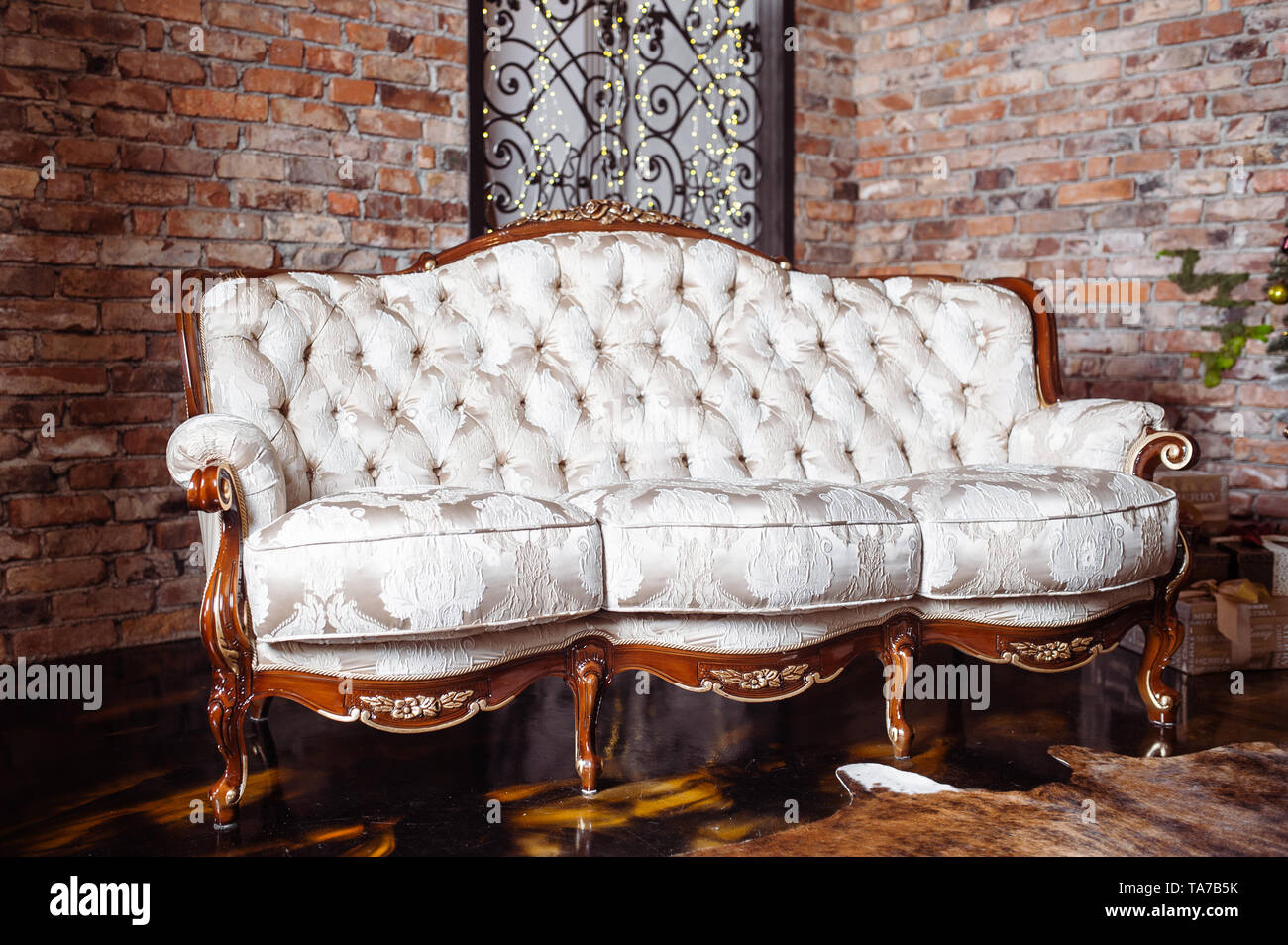 Luxuriöses, reichhaltiges Wohnzimmer-Design mit elegantem, klassischem Sofa und alter roter Ziegelwand Stockfoto