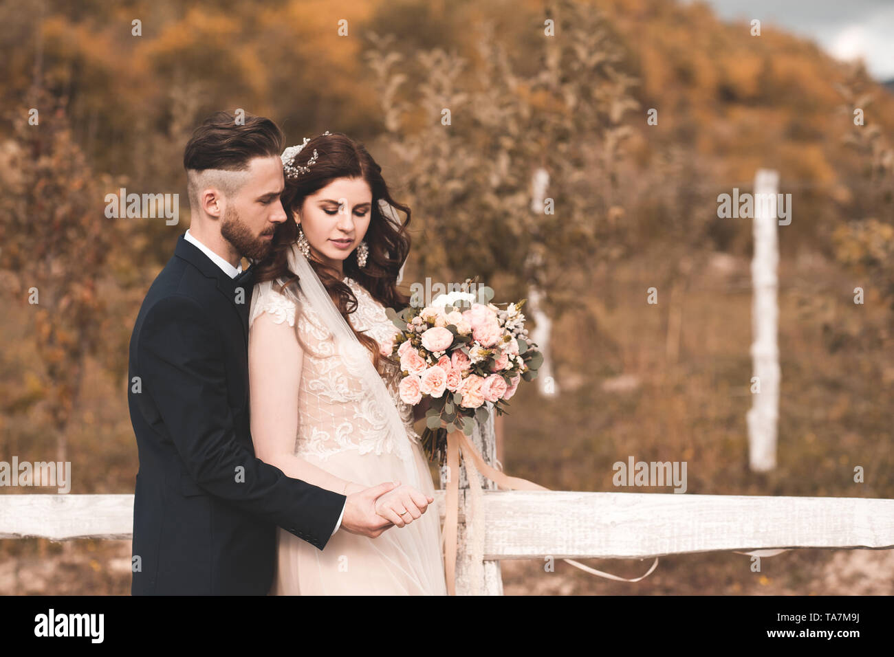 Stilvolle braut Holding weadding Blumenstrauß mit Bräutigam im Freien über Herbst Natur Hintergrund. Hochzeitstag. Feier. Stockfoto