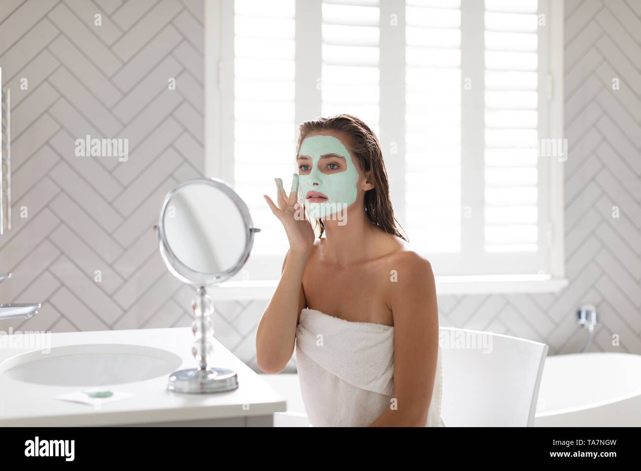 Frau im Spiegel und Anwendung der Maske nach dem Bad Stockfoto