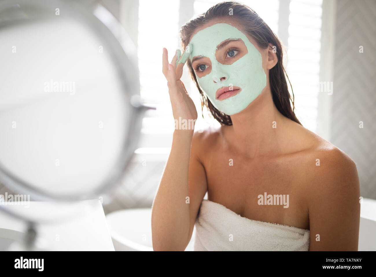 Frau im Spiegel und Anwendung der Maske nach dem Bad Stockfoto