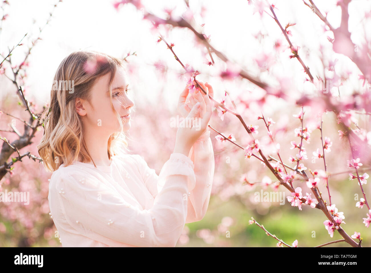 Schöne blonde teen Mädchen 15-16 Jahre alt in Peach Orchard Nahaufnahme posieren. Frühling Saison. Stockfoto
