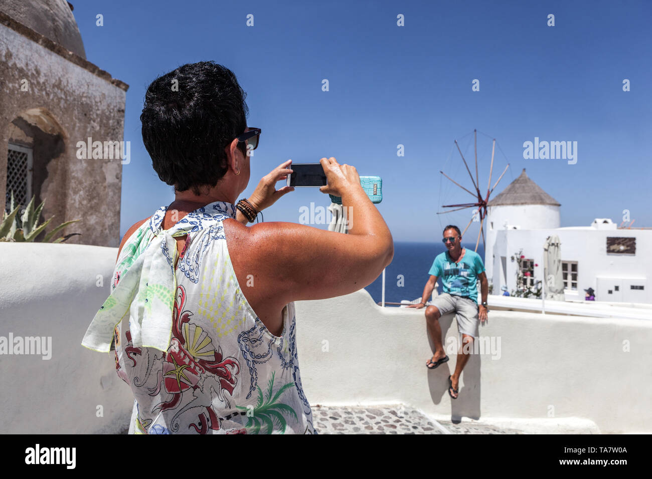 Frau, die ein Foto mit Blick auf die Windmühle macht Oia Santorini Touristen Griechische Insel Griechenland Urlaub Europa Senioren reisen Stockfoto